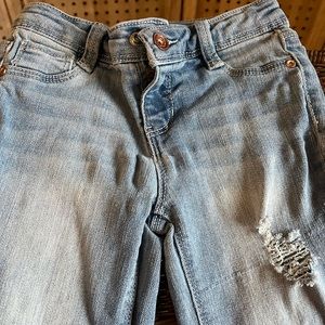 Girls denim jeans, ripped knees. Lighter washed denim with a tight fit on ankle